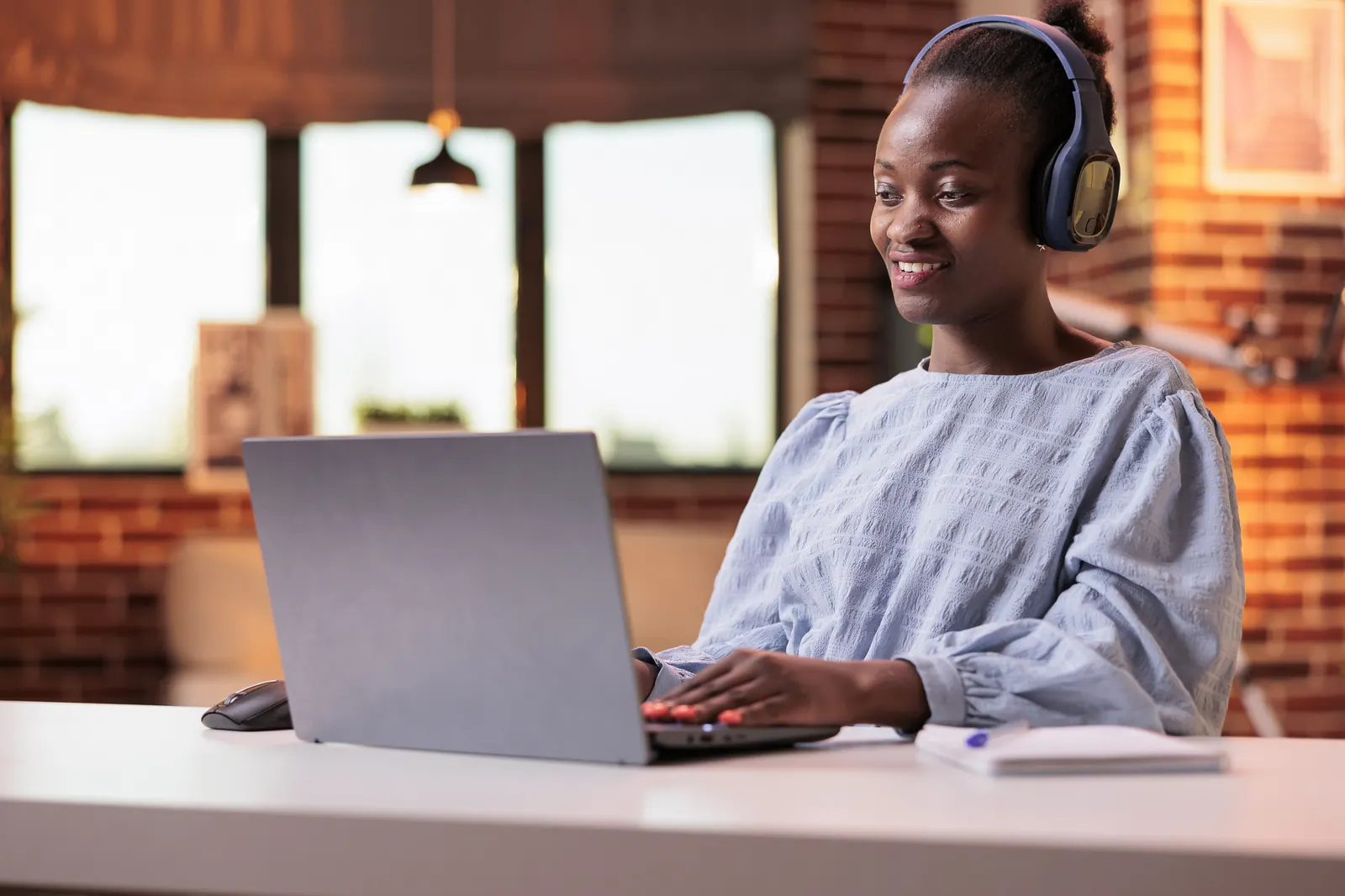 A student in headphones following an online class on her laptop